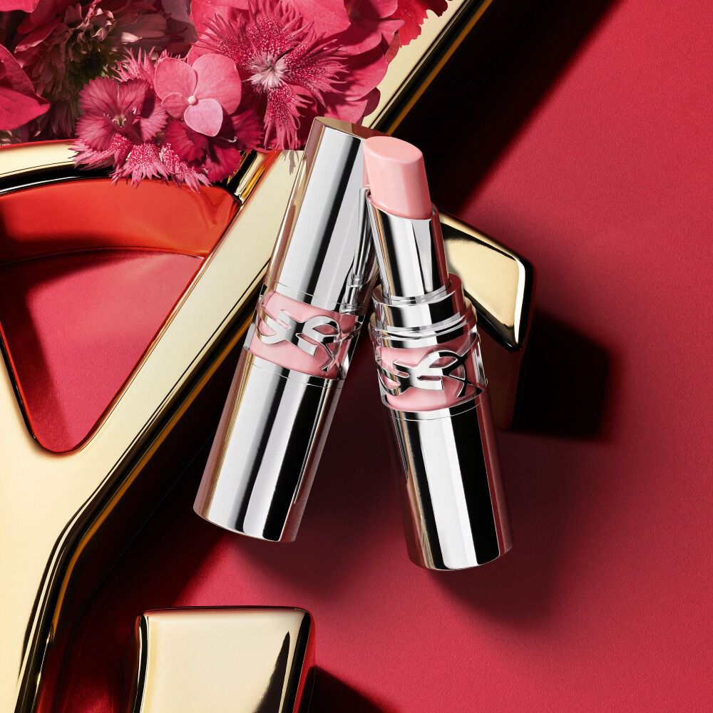 YSL Loveshine lipstick tono 44 en empaque plateado, abierto mostrando la barra rosa suave junto al tubo cerrado, decorado con flores rosas sobre fondo rojo con detalle del logo dorado de YSL.