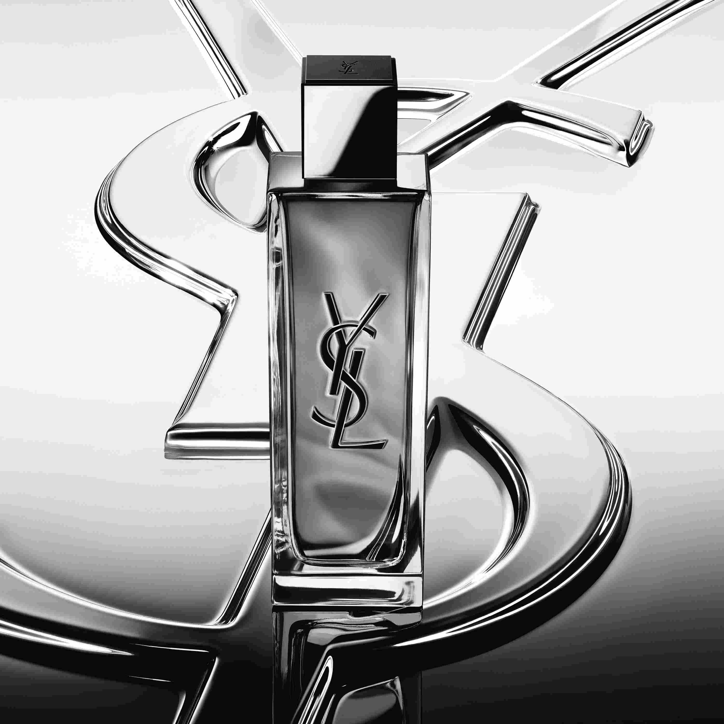 Frasco de perfume MYSLF sobre un gran logotipo cromado de YSL