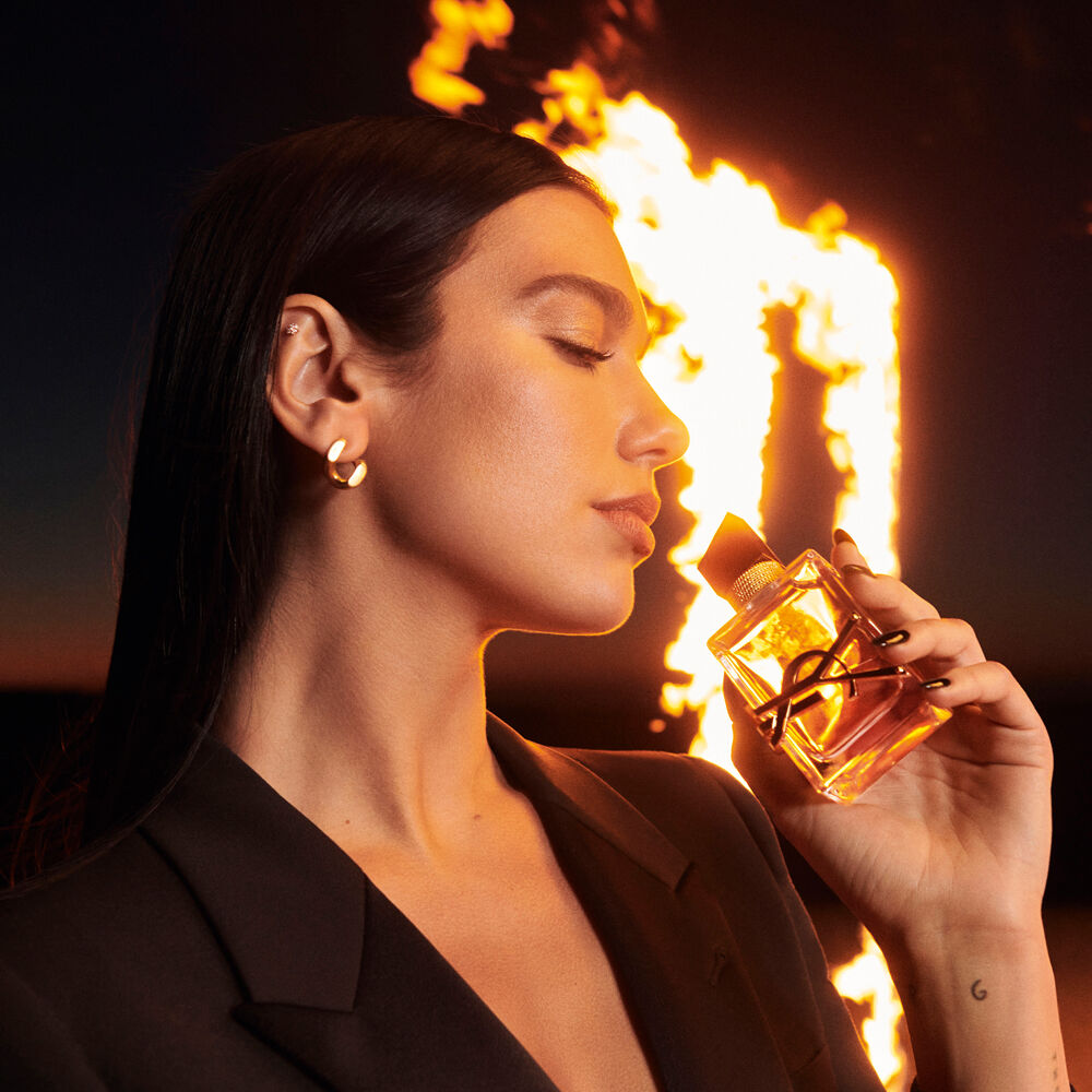Dua Lipa sosteniendo la fragancia Flowers and Flames