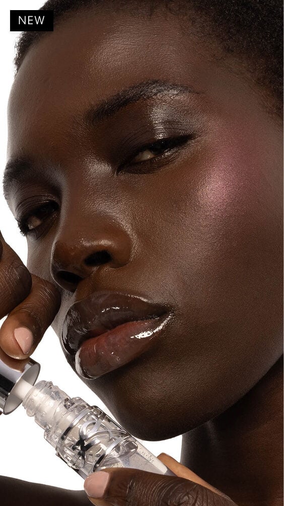 Nyaluak, de piel oscura, con YSL LOVESHINE Gloss en aceite labial voluminizador en el tono 11 Radiant Glass, luciendo labios brillantes.