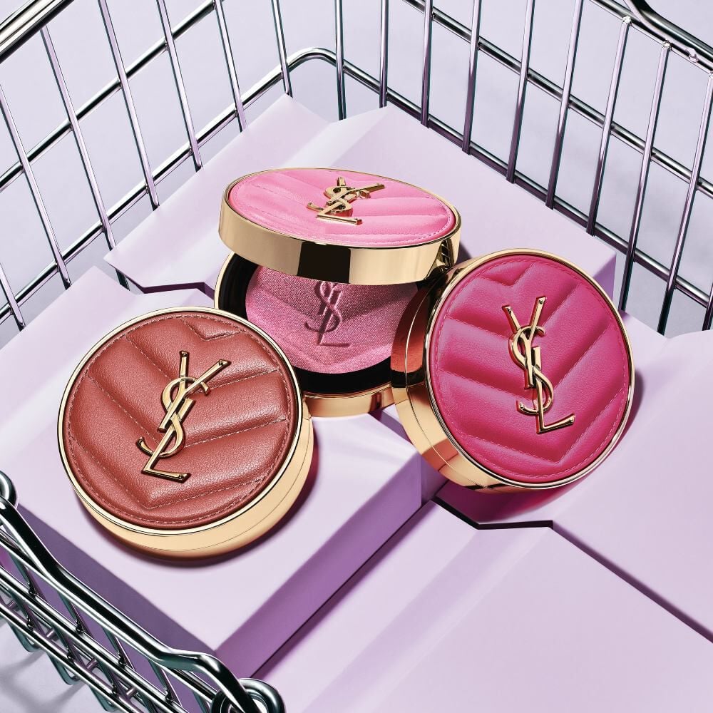 Tres coloretes en polvo YSL Make Me Blush en los tonos 10, 12 y 66, mostrados sobre bloques morados dentro de una canasta metálica.