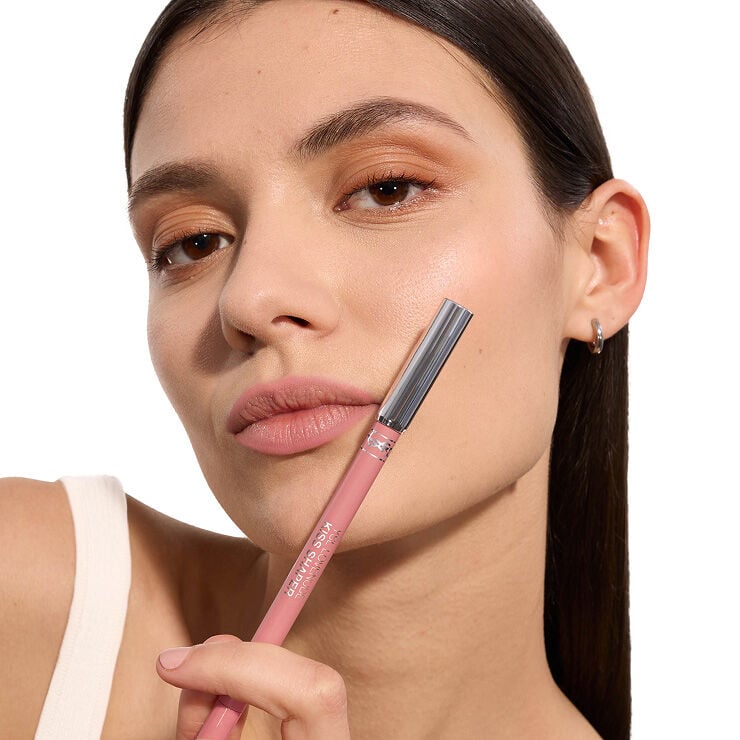 Adrienne usando YSL LOVENUDE Kiss Shaper, tono 44, en piel clara, sosteniendo el producto.