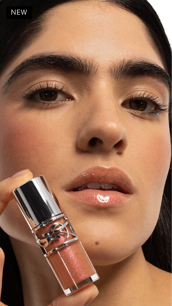 La mirada cautivadora de Natalia, labios adornados con YSL LOVESHINE Gloss en aceite labial voluminizador en el tono 12 Stardust, sosteniendo el producto cerca.