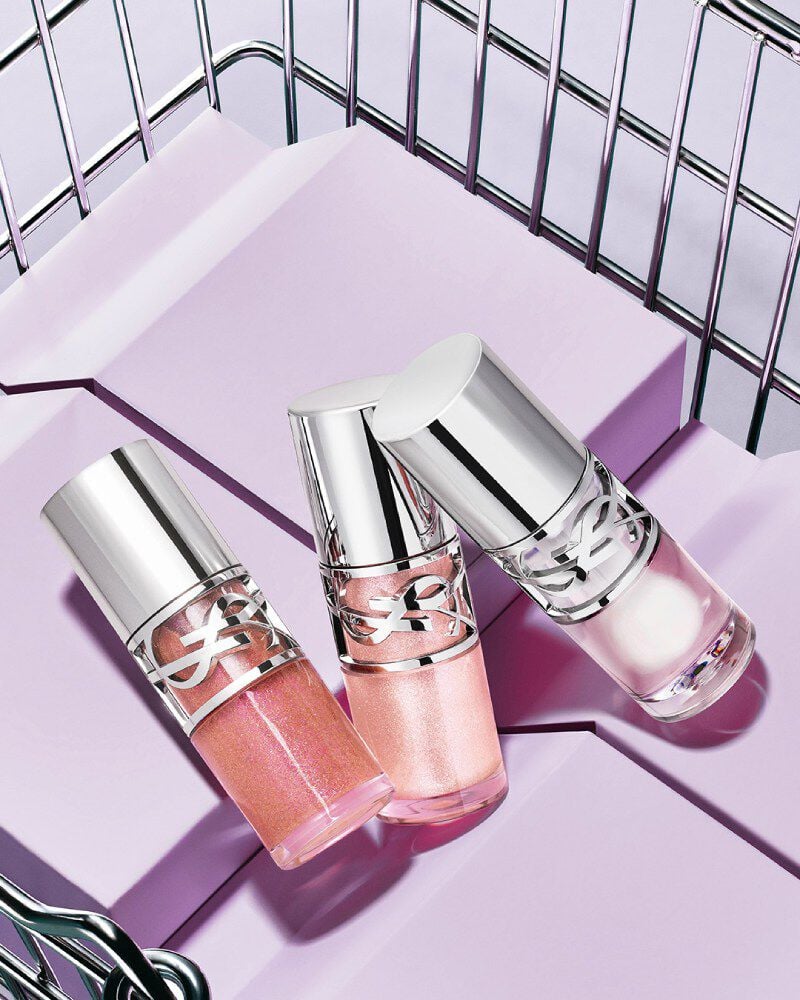 Tres labiales YSL Loveshine en los tonos 10, 11 y 12 mostrados sobre bloques morados dentro de una canasta metálica.