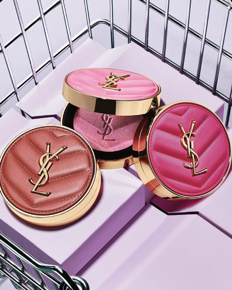 Tres coloretes en polvo YSL Make Me Blush en los tonos 10, 12 y 66, mostrados sobre bloques morados dentro de una canasta metálica.