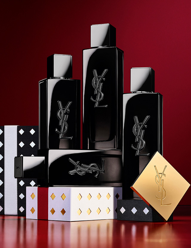 Multiple YSL LIBRE fragrance bottles layered over luxury gold-patterned Holiday gift packaging.
