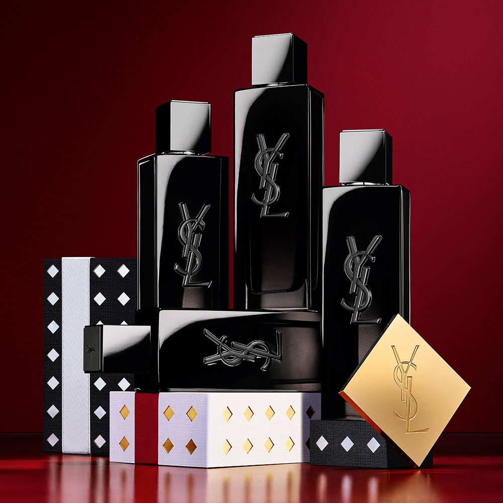 Multiple YSL LIBRE fragrance bottles layered over luxury gold-patterned Holiday gift packaging.
