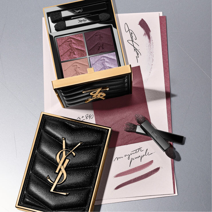Modelo mostrando las cajas de regalo de YSL Beauty en color negro con cintas rosas y rojas, junto con un neceser acolchado negro. 
